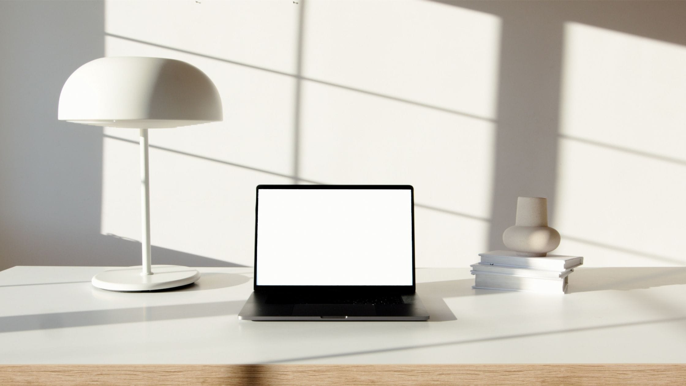 Minimalist desk setup with a laptop, white lamp, and books, perfect for starting a blog on WordPress with Bluehost.