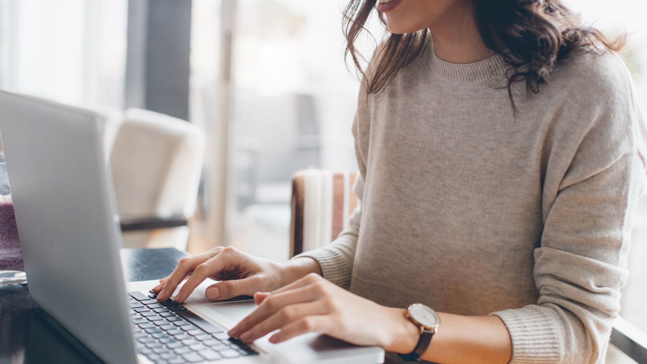 Person typing on a laptop in a cozy workspace