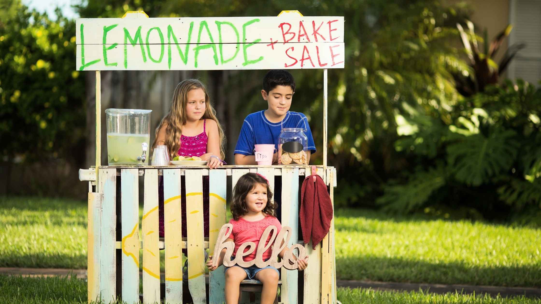 Kids selling lemonade and baked goods at a stand, showcasing how kids can make money with fun and creative ideas.