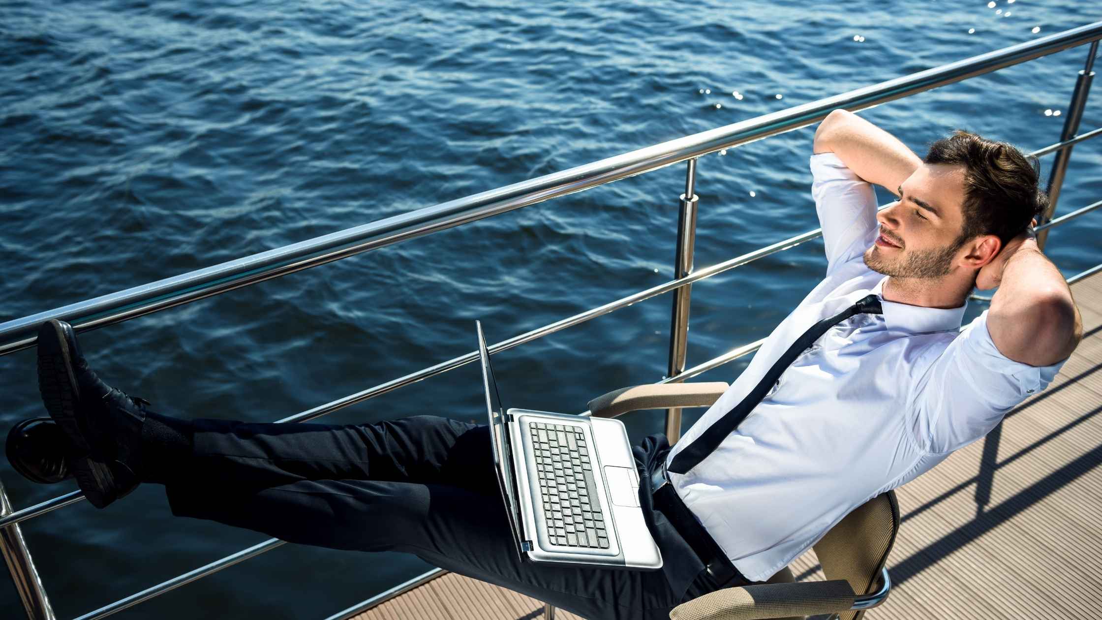 Entrepreneur relaxing on a yacht with a laptop, symbolizing freedom from million dollar business ideas.