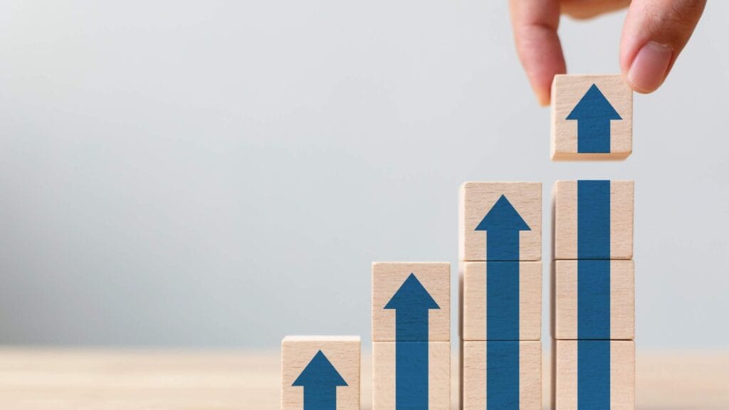 Wooden blocks with blue arrows stacked to show growth, representing million dollar business ideas and success.