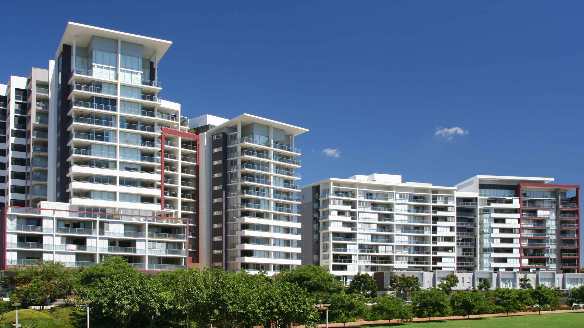 Modern apartment complex with trees in the foreground, representing a rental property for residual income opportunities.