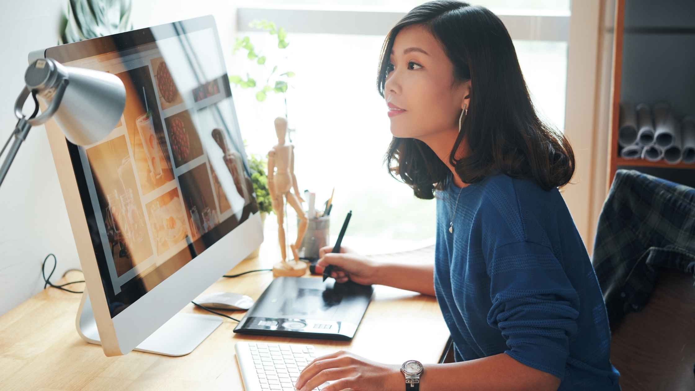 A tech-savvy woman working on graphic design at her computer in a home office.