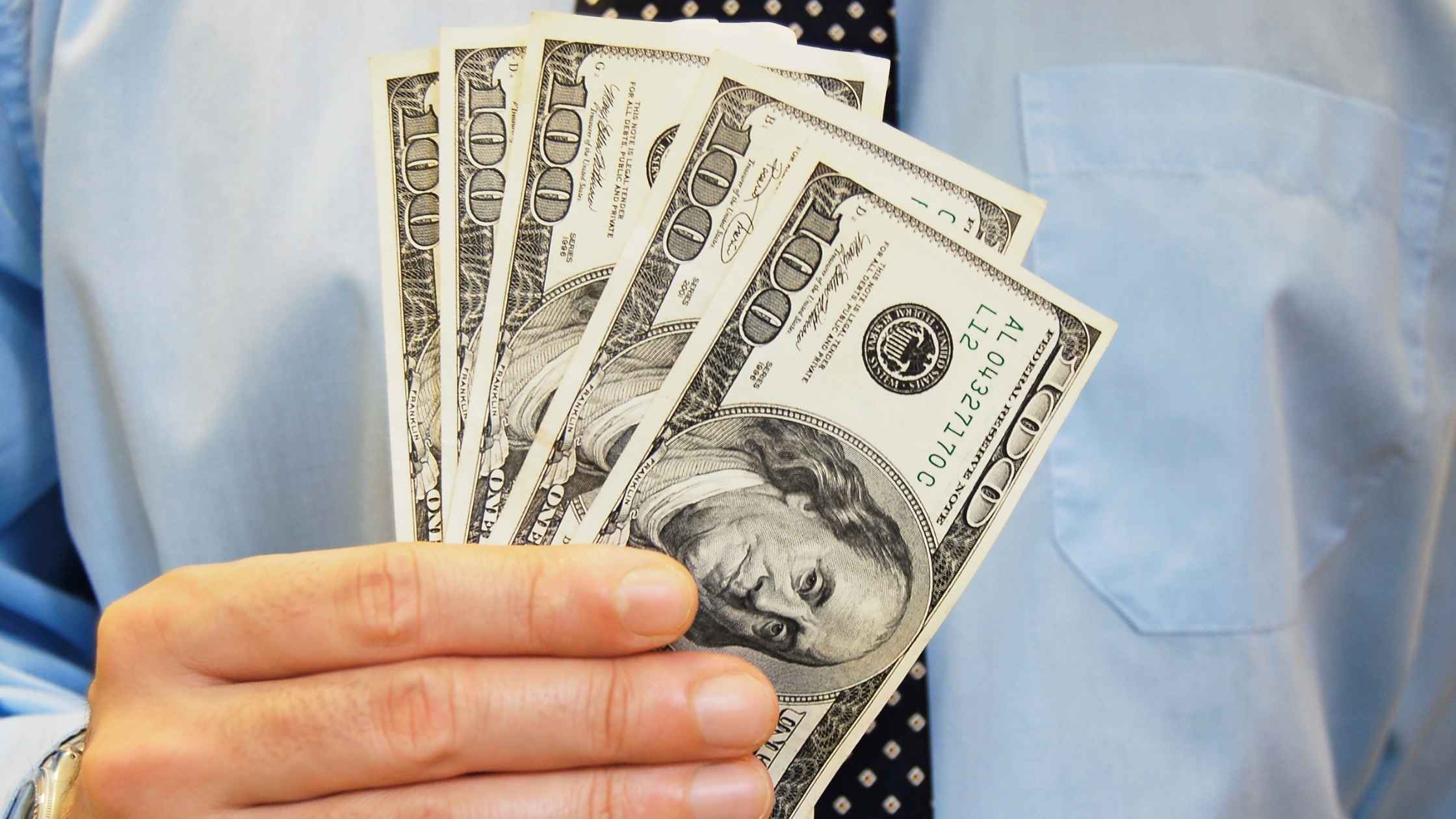 A person holding cash, representing earnings from retirement surveys.