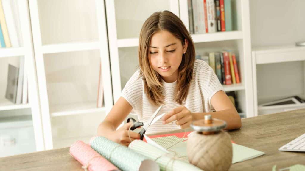 Person making handmade gifts with craft supplies, saving money by creating personal DIY presents.