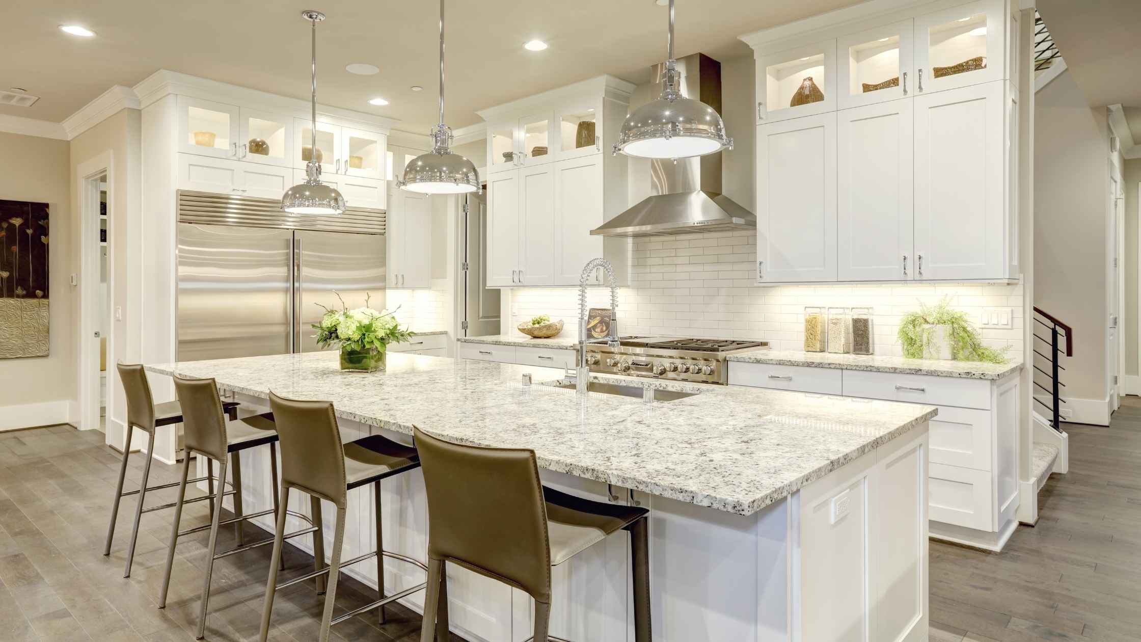 Bright DIY kitchen featuring white shaker cabinets, granite countertops, stainless steel appliances, and pendant lighting in a modern open layout.