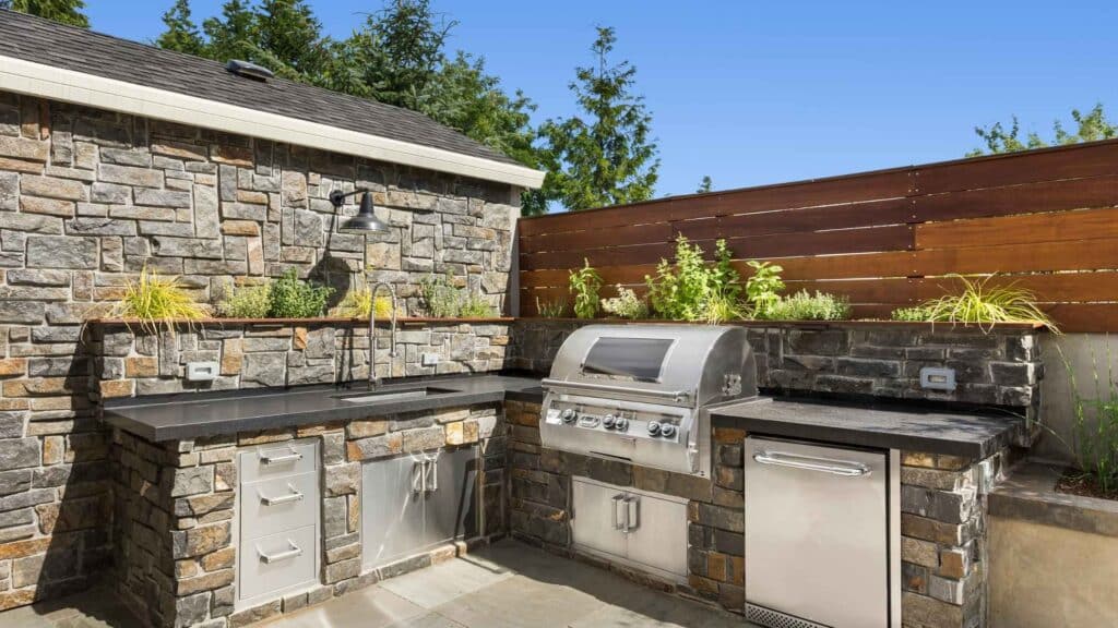 Outdoor kitchen island with stone design, built-in grill, and stainless steel appliances