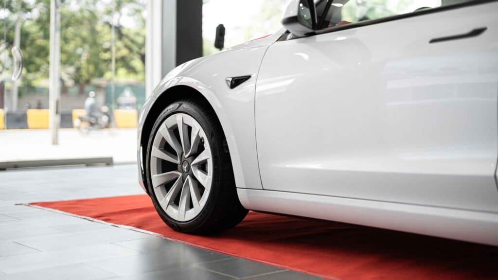 Close-up of a sleek white car on a red carpet in a showroom, representing the goal of paying off a car faster and owning it outright.