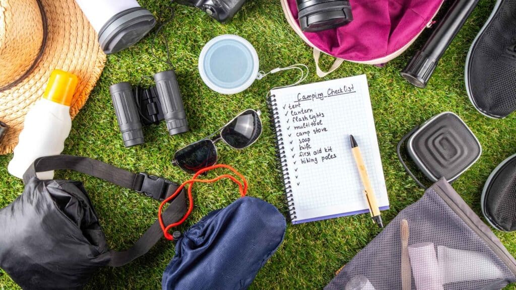 Essential gear checklist laid out on grass for a summer bucket list 2025 adventure