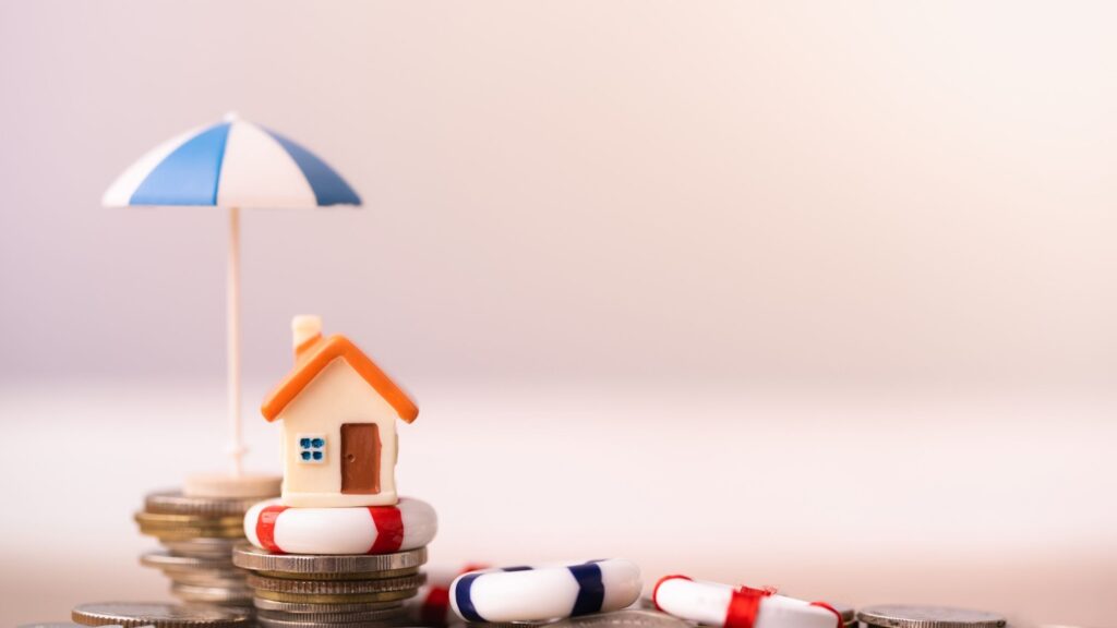 An image of a house on top of money and floating on a raft, which represents insurance protecting things like your home.