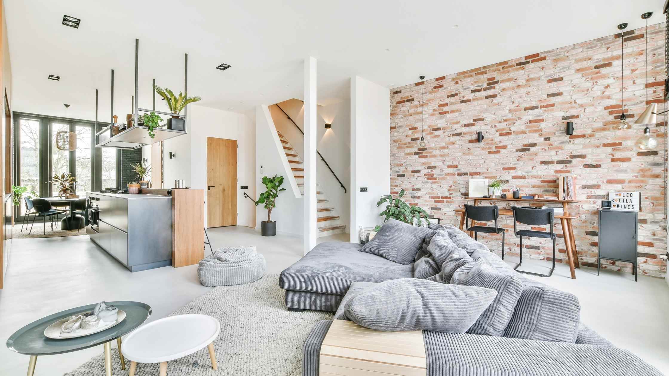 Modern open-concept space featuring living room decor inspo with brick wall, gray sectional, and stylish accents.
