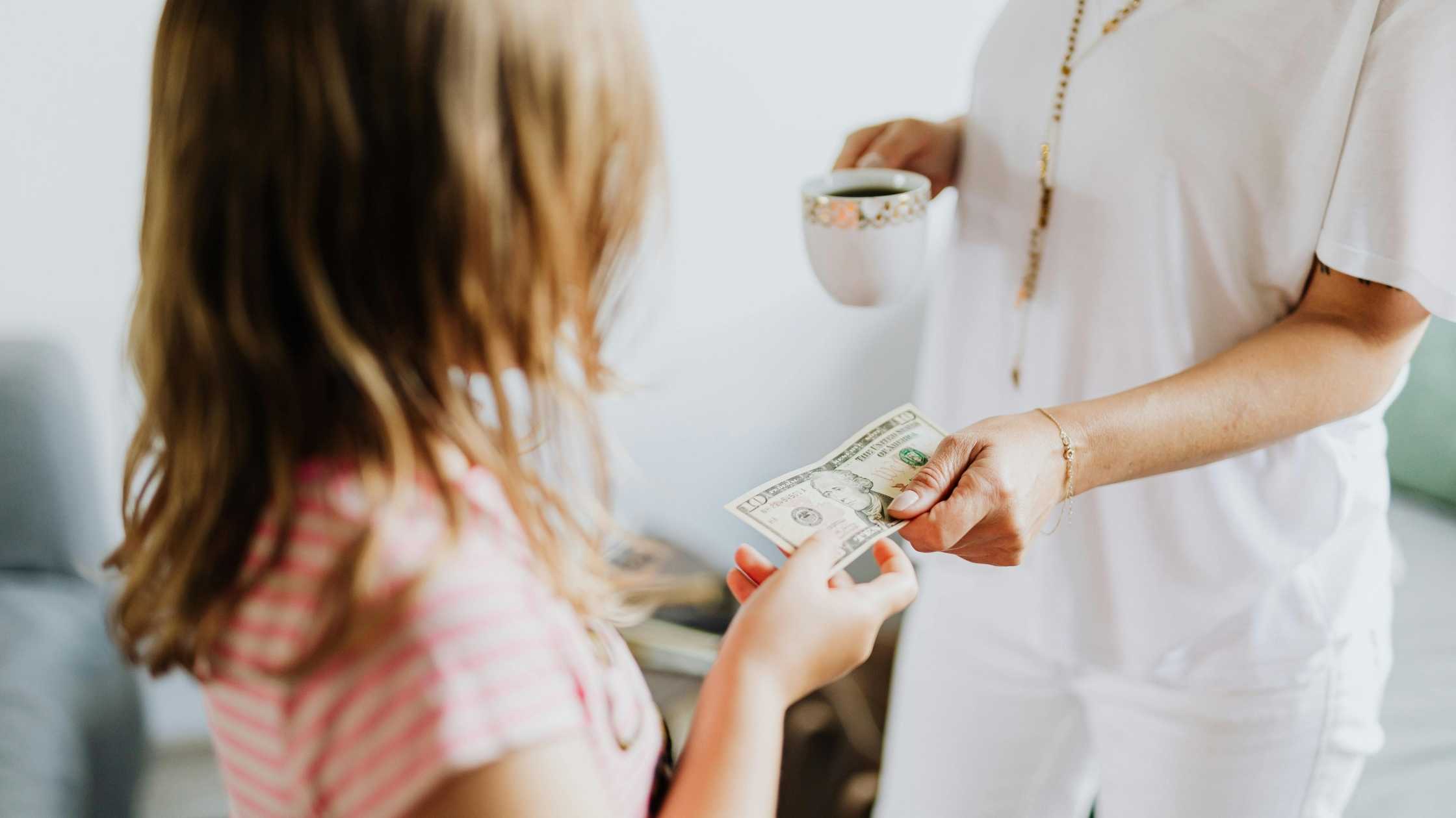 Child receiving cash from adult – illustrating ways to make extra money as a kid