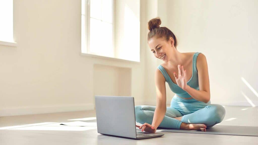 A woman doing yoga in her home working remotely with her online business that she started which represents being able to work from home without a credential.