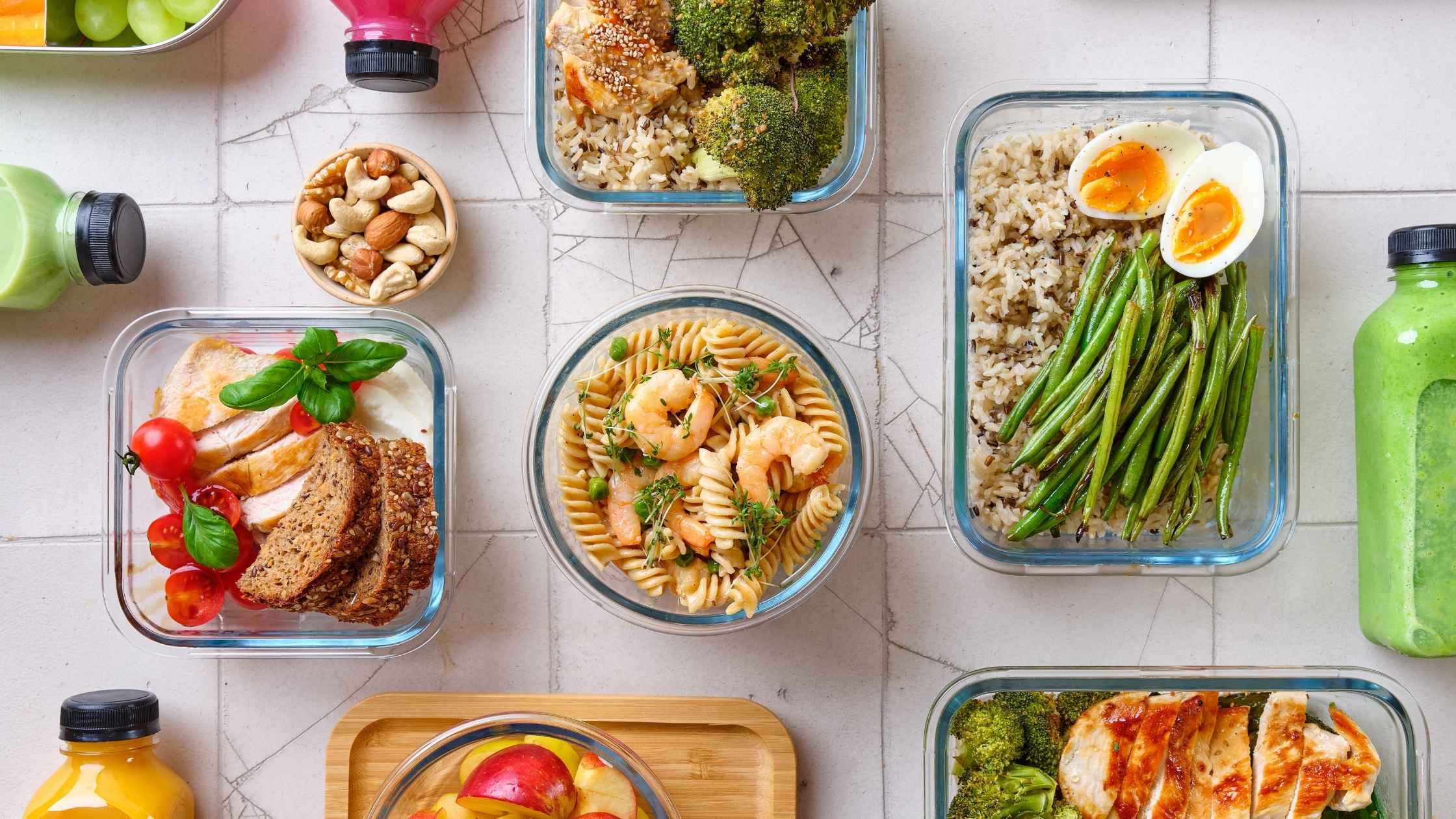 Meal-prepped cheap dinners for a family including rice, pasta, vegetables, and lean protein in glass containers.