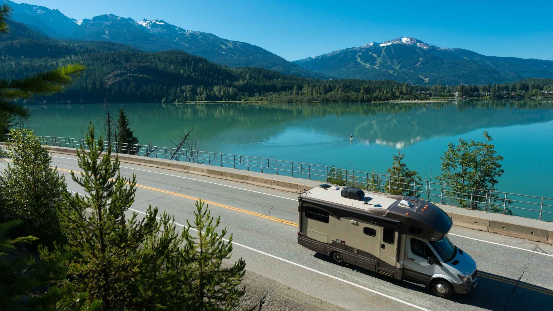 RV living on a scenic mountain highway beside a crystal-clear lake